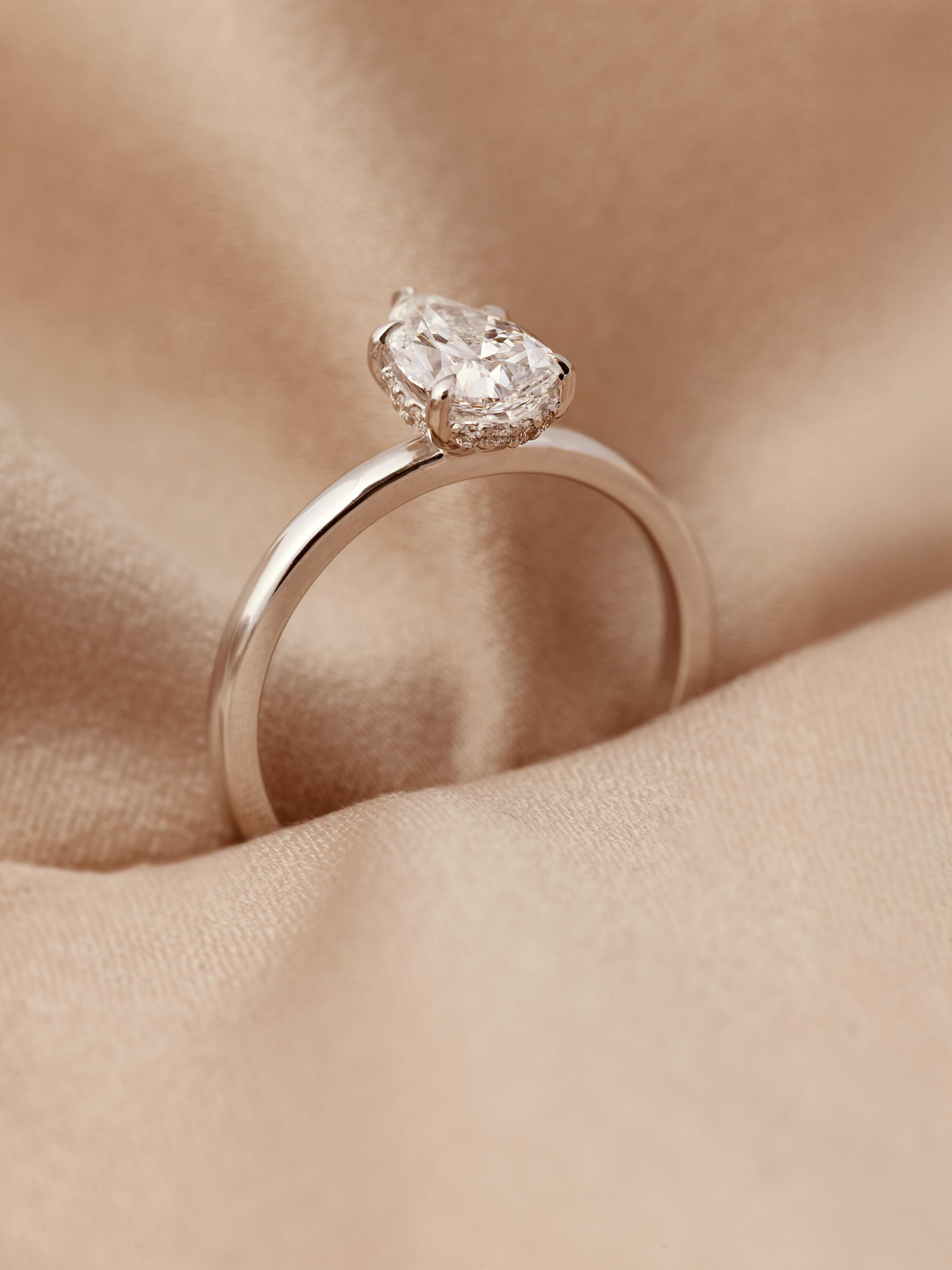 Vero Nuovo Pære er en eksklusiv forlovelsesring med fem elegante klør som fremhever og sikrer hoveddiamanten. Den klassiske formen kombineres med moderne detaljer for et sofistikert uttrykk som skiller seg ut.
Ringen har også en diskret «hidden halo» – et glitrende bånd av diamanter under hovedstenen som tilfører ekstra eksklusivitet og lys.